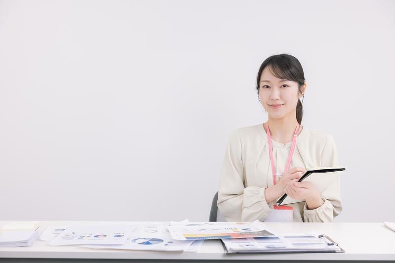 資料を手に微笑む女性（学びのイメージ）